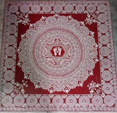 a red and white table cloth with an intricate design on the center, surrounded by flowers