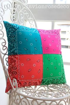 two colorful pillows sitting on top of a white chair