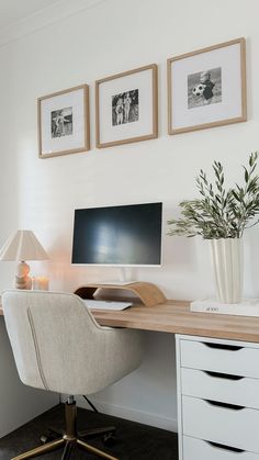 a desk with a computer on it in front of three framed pictures and a lamp