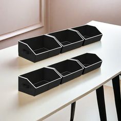 three black boxes sitting on top of a white table