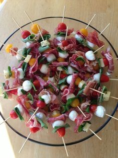 a glass plate topped with meat and veggies on skewered toothpicks