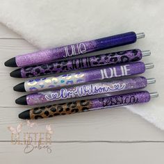 five pens with different designs on them sitting next to each other in front of a white towel