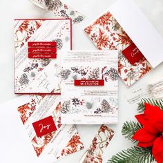 some red and white christmas cards on top of each other next to a poinsetti