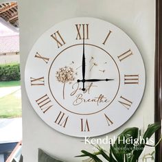 a clock with the words breathe and dandelions on it is hanging from a wall