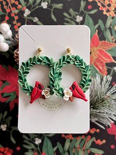 two christmas wreaths with red birds on them sitting in front of a floral background