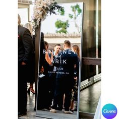 a man standing in front of a large mirror with flowers on it's side