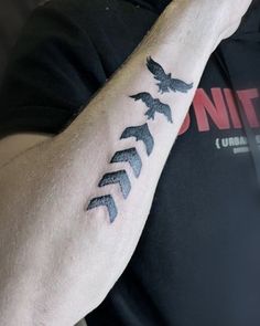 a man with a tattoo on his arm that has birds flying in the same direction