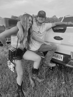 a man and woman sitting on the back of a pick up truck with their arms around each other