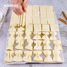 a person is cutting up some food on a sheet of wax paper with a pair of tongs