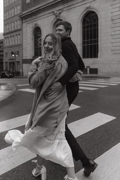 a man and woman walking across a cross walk