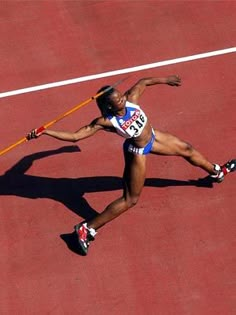 a woman is running on a track with a stick in her hand and holding onto the pole