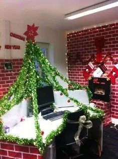 an office decorated for christmas with a tree on the desk and computer in front of it