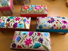 four colorfully painted stools sitting on top of a wooden floor