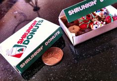 an unopened box of donuts next to a penny on a counter top