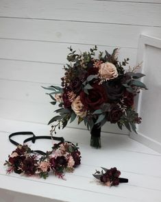 a bridal bouquet and two flower crowns on a white bench next to a pair of black headbands