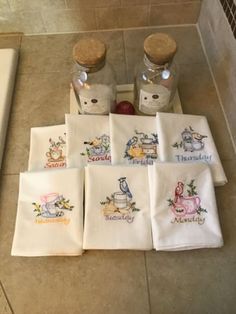 embroidered tea towels are sitting on the floor next to two bottles and some salt shakers