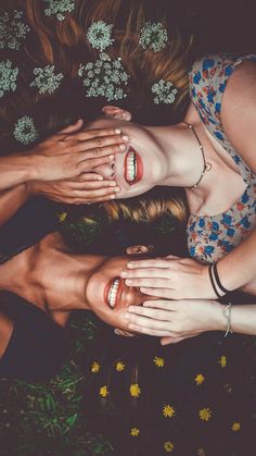 three young women laying on the ground with their hands around each other's heads