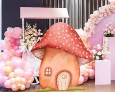 a birthday party with balloons and decorations including a mushroom house on the floor next to a balloon arch