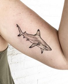 a man's arm with a black and white tattoo of a shark on it