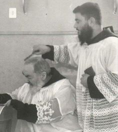 an old black and white photo of two men in medieval garb, one is combing the other's hair