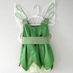 a green fairy dress hanging on a wall