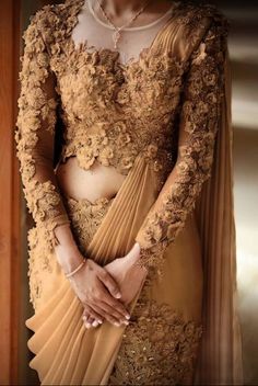 a woman in a brown and gold sari with her hands on her hips, posing for the camera