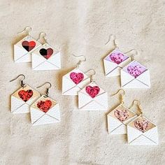 six different earrings with hearts in them on a white surface, one is open and the other two are closed