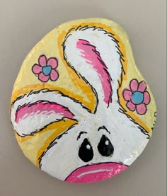 a painted rock with a face and flowers on it