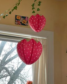 three paper lanterns hanging from the ceiling in front of a window