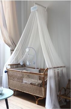 a baby crib with mosquito netting hanging from the ceiling