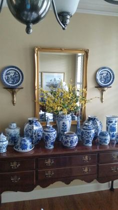 blue and white vases are sitting on a table in front of a large mirror