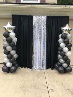 two black and white balloons with silver stars on them are standing in front of a door