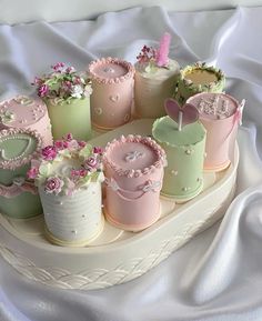 there are many small cakes on the plate with pink and green frosting, decorated with flowers