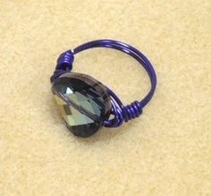 a purple ring with a faceted black diamond on the top and blue wire around it