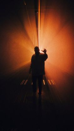 a person standing in the middle of a dark room with light coming from behind them