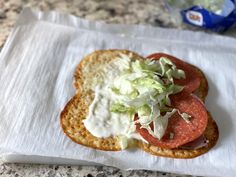 two slices of bread with lettuce and tomato on top sitting on a napkin