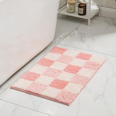 a bath tub sitting next to a white toilet in a bathroom with pink rugs on the floor