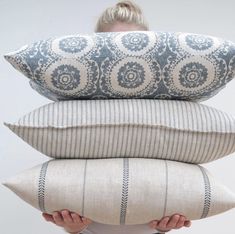 a woman holding three pillows in front of her face, both with different patterns on them