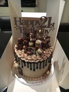 a birthday cake decorated with chocolate and marshmallows is displayed in a box