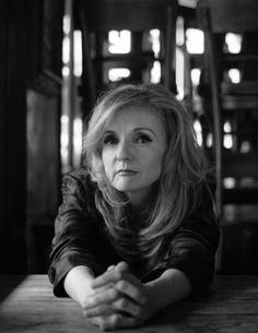 a woman sitting at a table with her hands folded out in front of her face