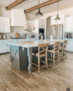 a large kitchen with an island in the middle and wooden chairs at the counter top