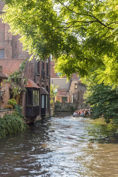 a river running through a small town next to tall brick buildings with windows on each side