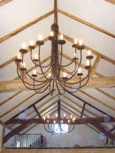 a chandelier hanging from the ceiling in a room with exposed beams and wooden beams