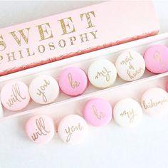 pink and white candies with gold lettering in a box next to a candy bar