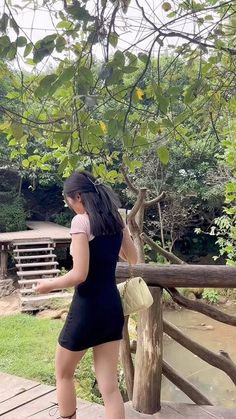 a woman standing on top of a wooden bridge