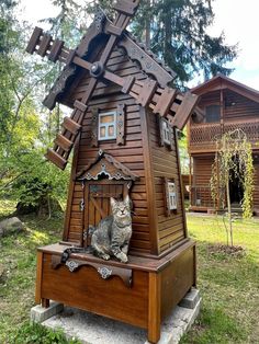 a cat sitting on top of a wooden structure in front of a building with a windmill