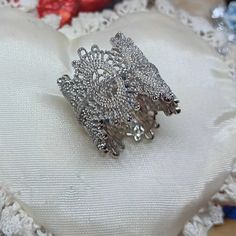 a silver brooch sitting on top of a white pillow