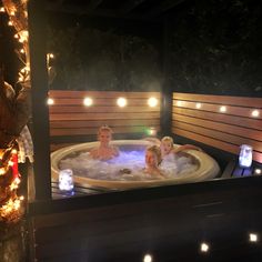 three people in a hot tub surrounded by christmas lights