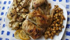 a white plate topped with chicken, chickpeas and orange slices next to a fork