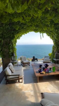 an outdoor living area with couches, tables and water in the backround